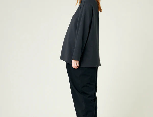 Person wearing a black outfit with a plain background