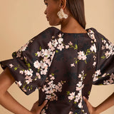 Model wearing floral puff sleeve tiered midi dress in chocolate blossom print.