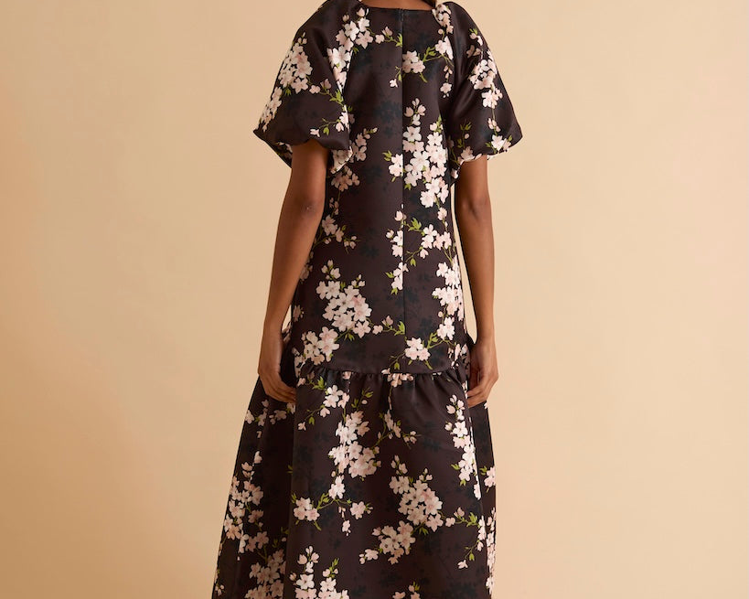 Model wearing floral puff sleeve tiered midi dress in chocolate blossom print.