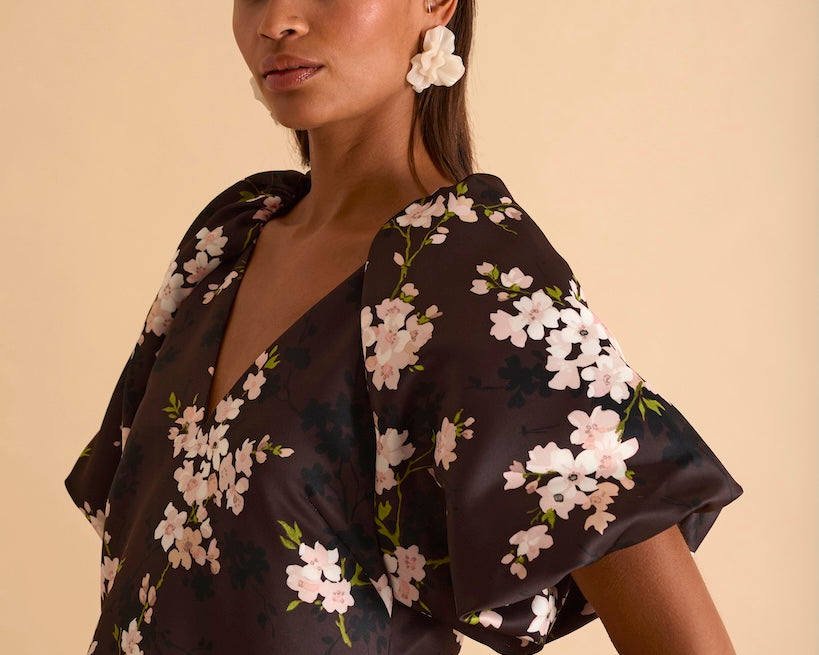Model wearing floral puff sleeve tiered midi dress in chocolate blossom print.