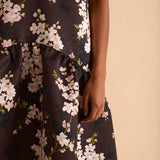 Model wearing floral puff sleeve tiered midi dress in chocolate blossom print.