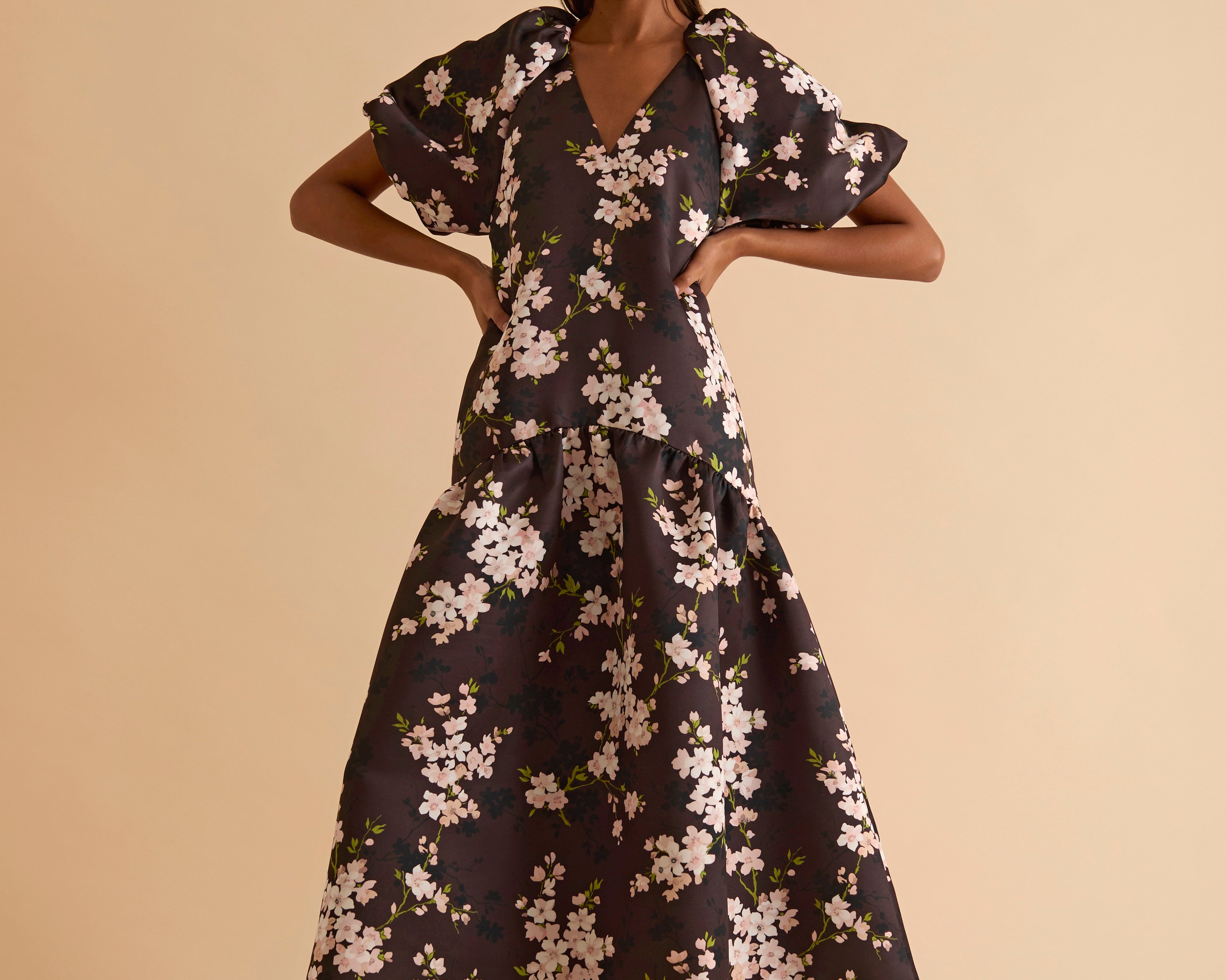 Model wearing floral puff sleeve tiered midi dress in chocolate blossom print.