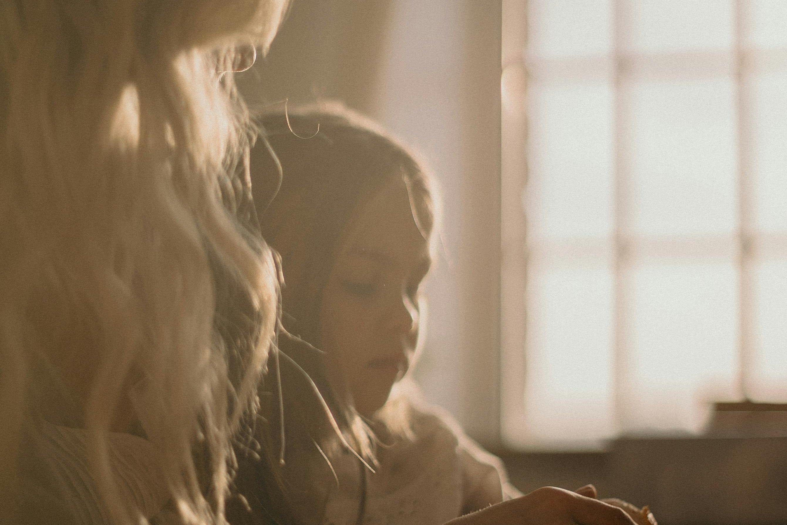 A mother and daughter sit beside a window