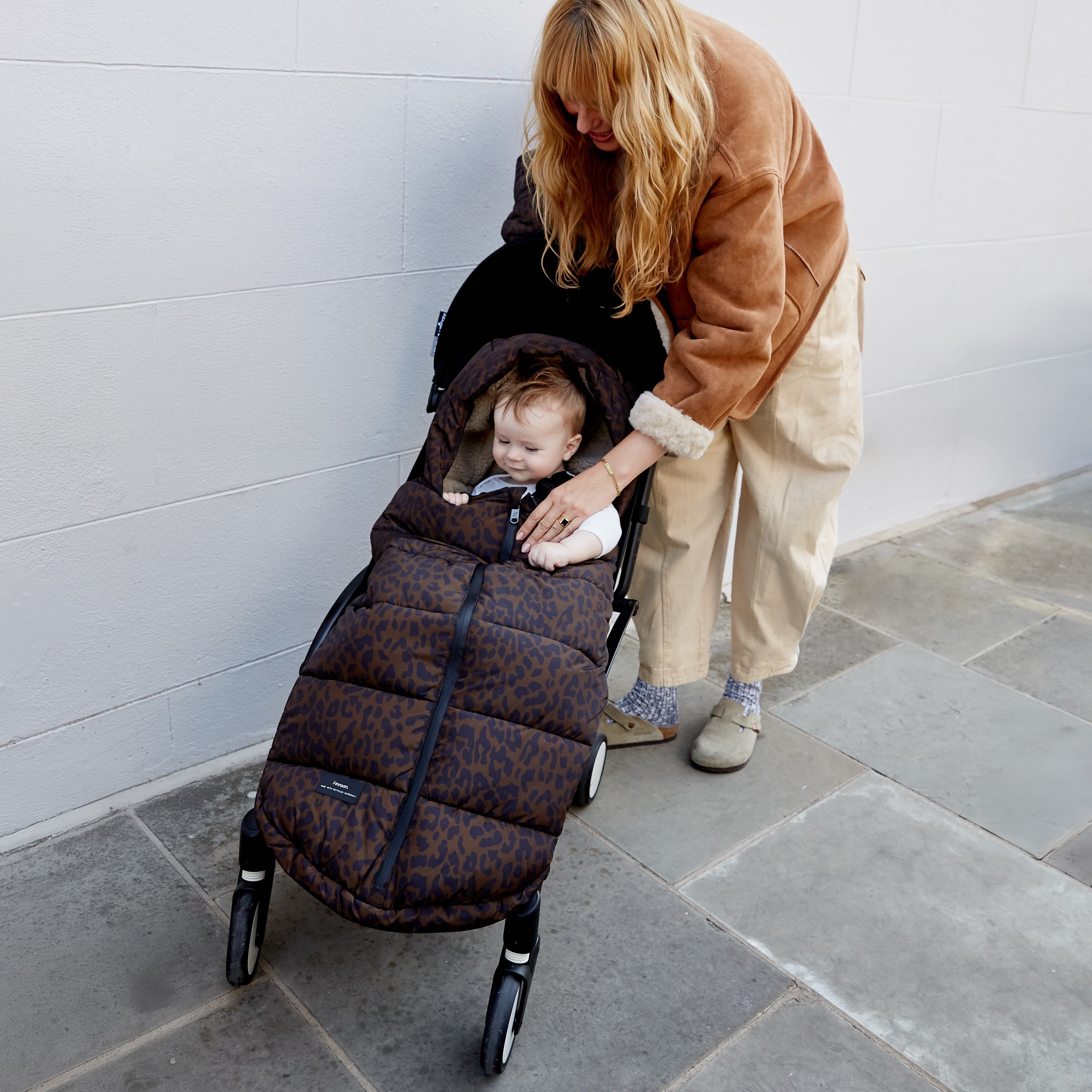 Woman pushing a stroller with a Finnson quilted footmuff liner