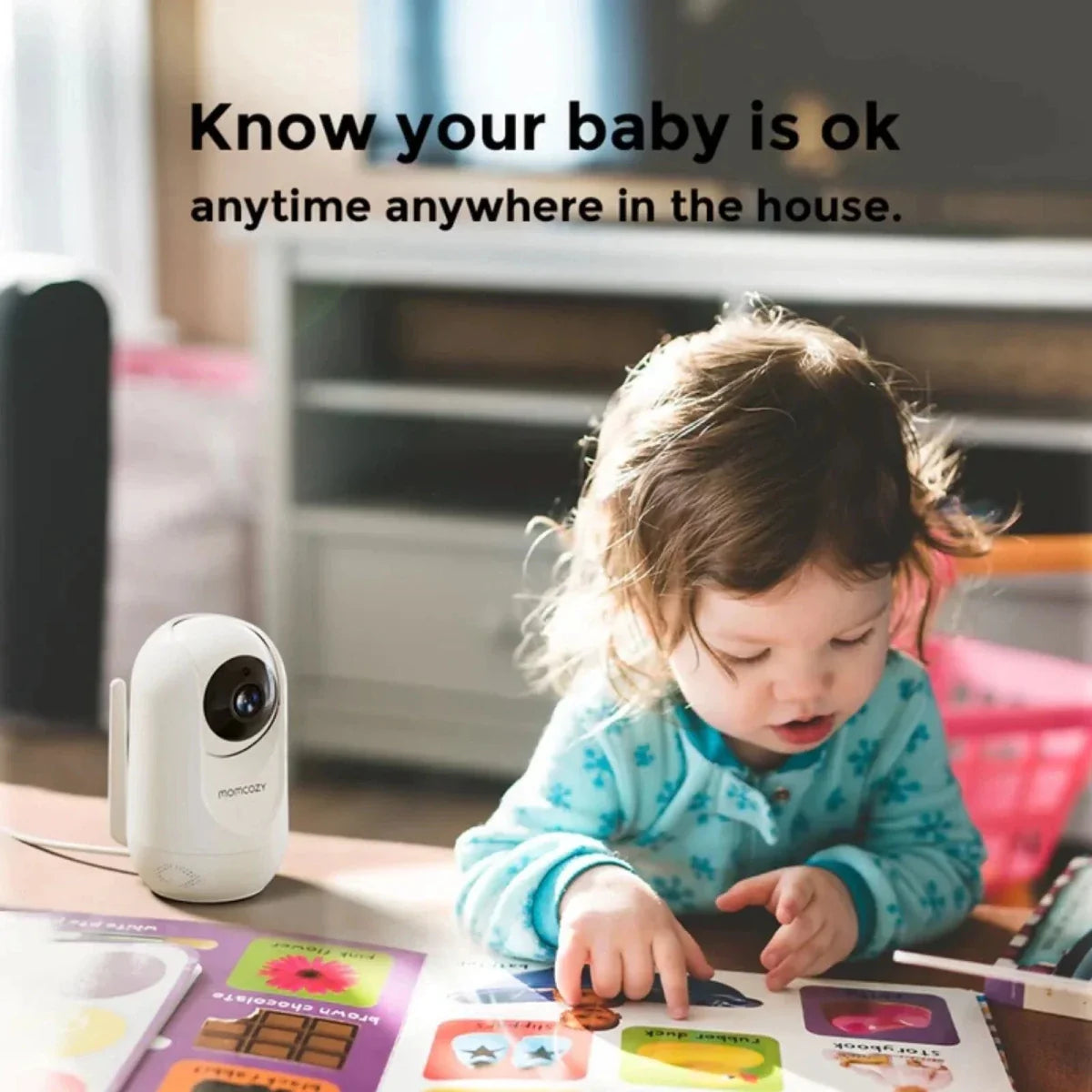 Child playing with a toy on a table next to a security camera with text 'Know your baby is ok anytime anywhere in the house'.