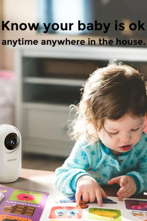 Child playing with a toy on a table next to a security camera with text 'Know your baby is ok anytime anywhere in the house'.