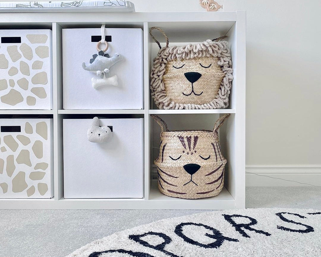 Natural Tiger Belly Basket on a white shelving unit in a nursery, below a lion basket, with a patterned round rug in front