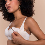 Woman wearing a white bra against a beige background