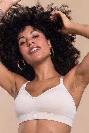 Woman wearing a white bralette against a beige background