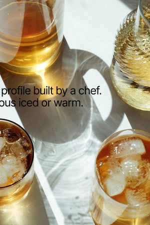 Four glasses of iced and warm beverages on a white surface with text about a chef's taste profile.