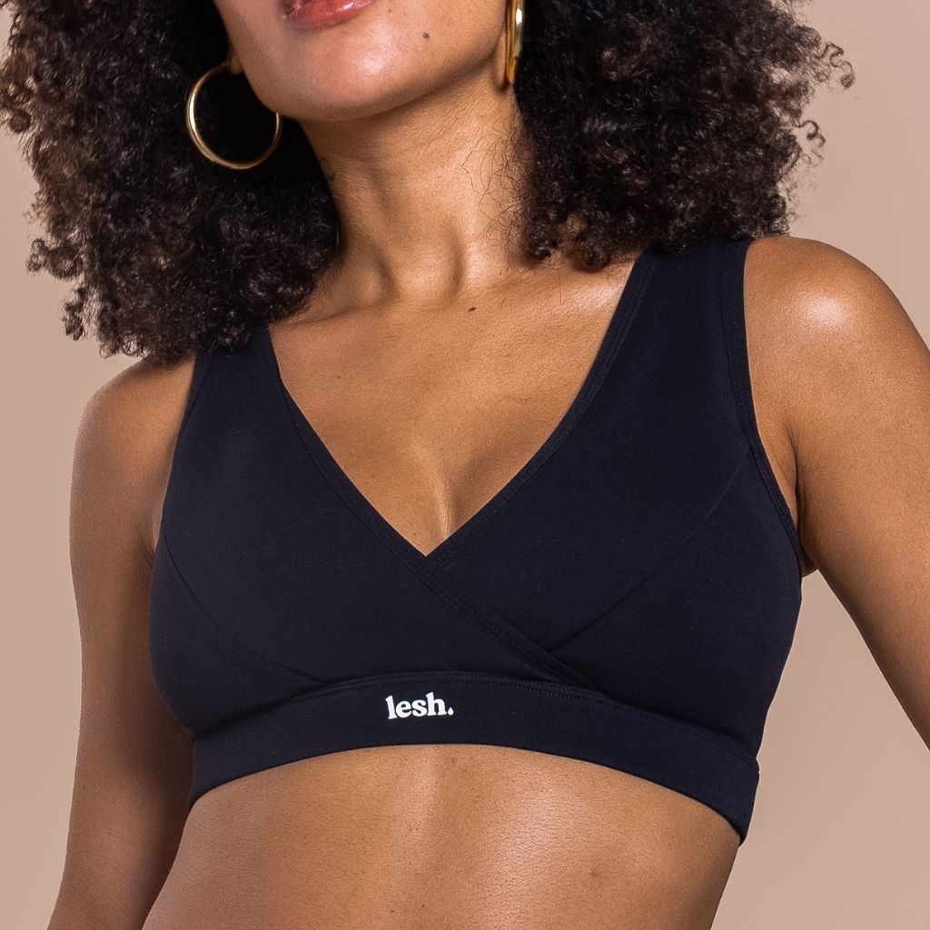 Woman wearing a black sports bra with 'lesh' branding on a beige background