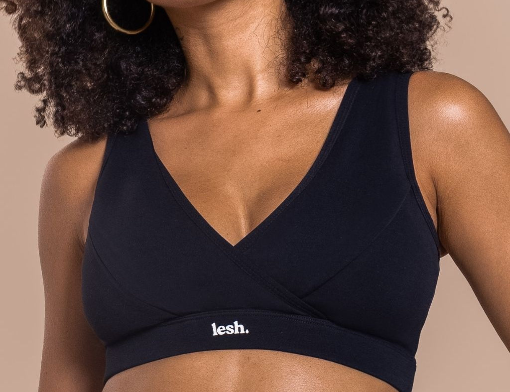 Woman wearing a black sports bra with 'lesh' branding on a beige background