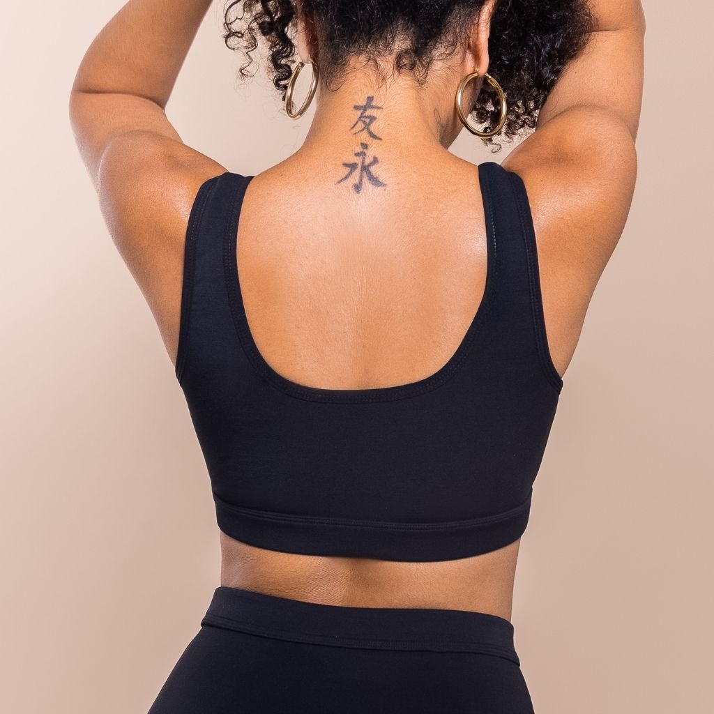 Person wearing a black sports bra with a beige background