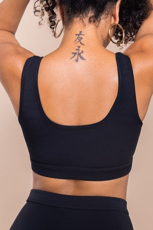 Person wearing a black sports bra with a beige background