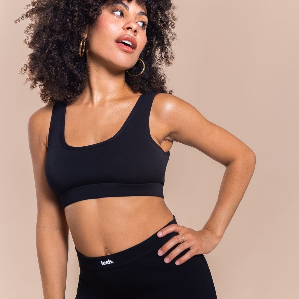 Woman wearing a black sports bra and leggings on a beige background