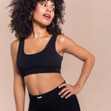 Woman wearing a black sports bra and leggings on a beige background