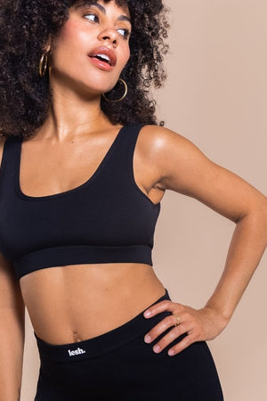 Woman wearing a black sports bra and leggings on a beige background