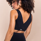 Woman wearing a black sports bra with 'lees' branding on a beige background