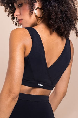Woman wearing a black sports bra with 'lees' branding on a beige background