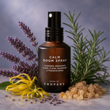 Calm Room Spray in a brown glass bottle with black pump, surrounded by lavender, rosemary, ylang ylang and frankincense