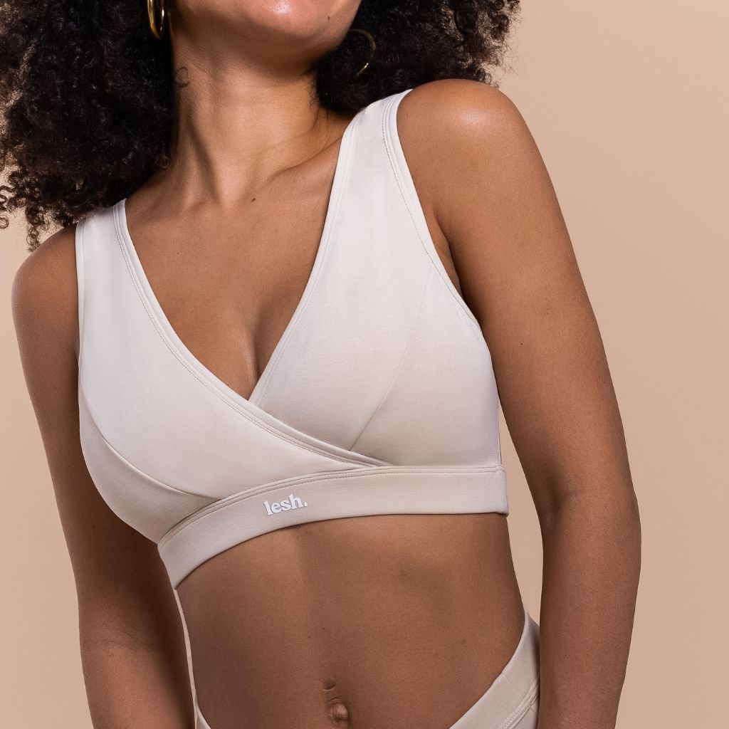 Woman wearing a beige bralette with 'fesh' branding on a beige background
