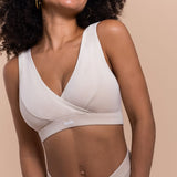 Woman wearing a beige bralette with 'fesh' branding on a beige background