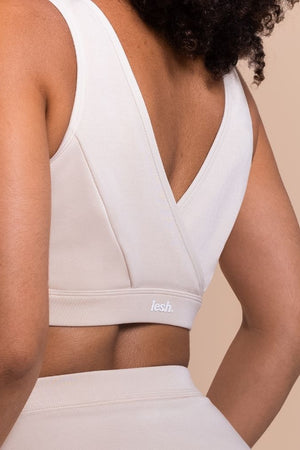 White sports bra with 'flesh' branding on a beige background