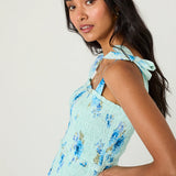 Woman wearing a light blue floral dress against a plain background