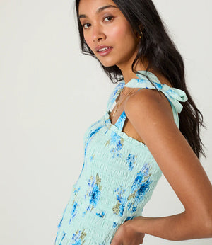 Woman wearing a light blue floral dress against a plain background