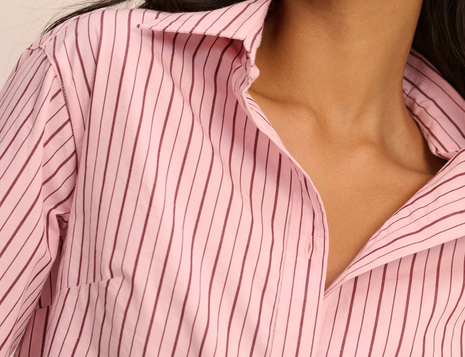 Close-up of a person wearing a pink and white striped shirt.