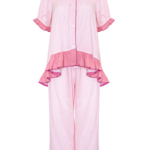 A light pink two-piece pajama set featuring a short-sleeve button-front top with ruffled trim and matching wide-leg pants with ruffled hems, shown on a plain white background.