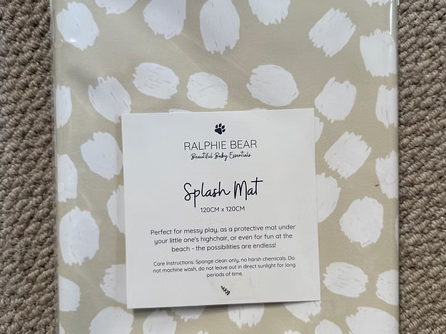 Packaged Ralphie Bear Splash Mat with white abstract pattern on a beige background