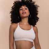 Woman wearing a beige bralette with a brand logo on a beige background
