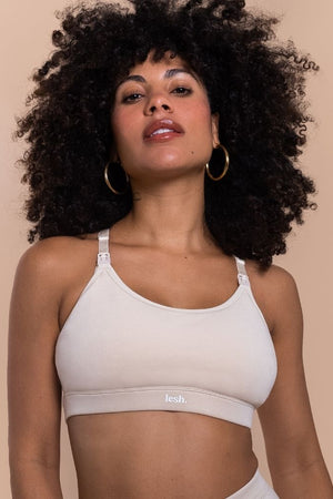 Woman wearing a beige bralette with a brand logo on a beige background