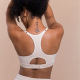 Person wearing a white sports bra with cut-out design on a beige background