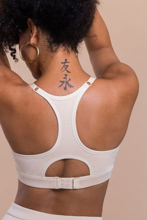 Person wearing a white sports bra with cut-out design on a beige background