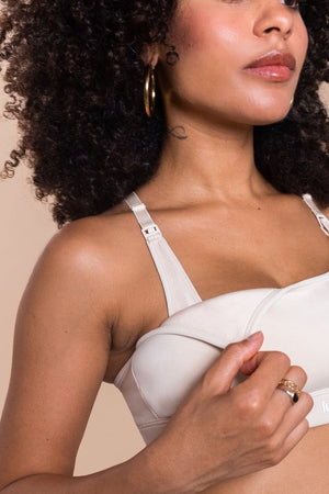 Woman wearing a white bra against a beige background