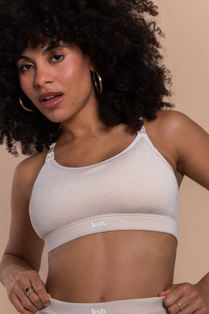 Woman wearing a white sports bra and underwear set with 'lesh' branding on a beige background
