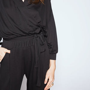 Person wearing a black outfit with a plain background