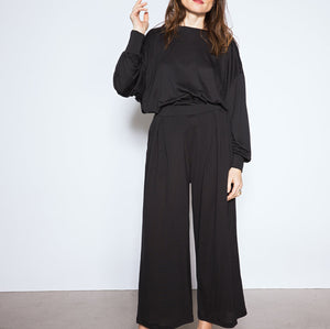 Woman wearing a black outfit standing against a white background