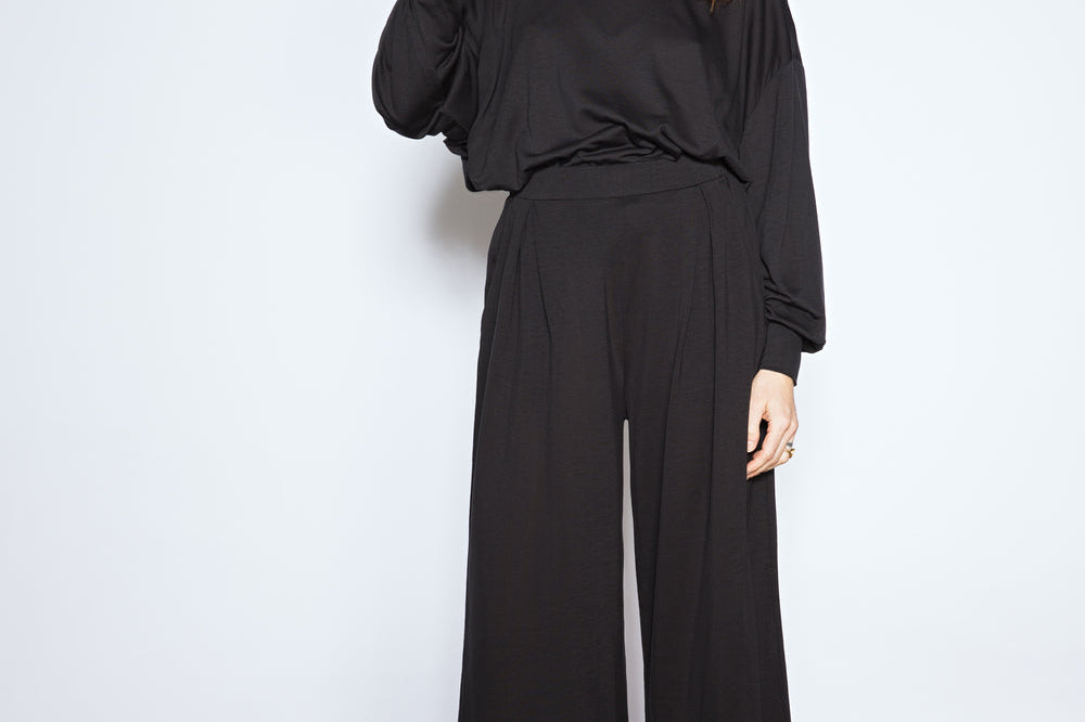 Woman wearing a black outfit standing against a white background