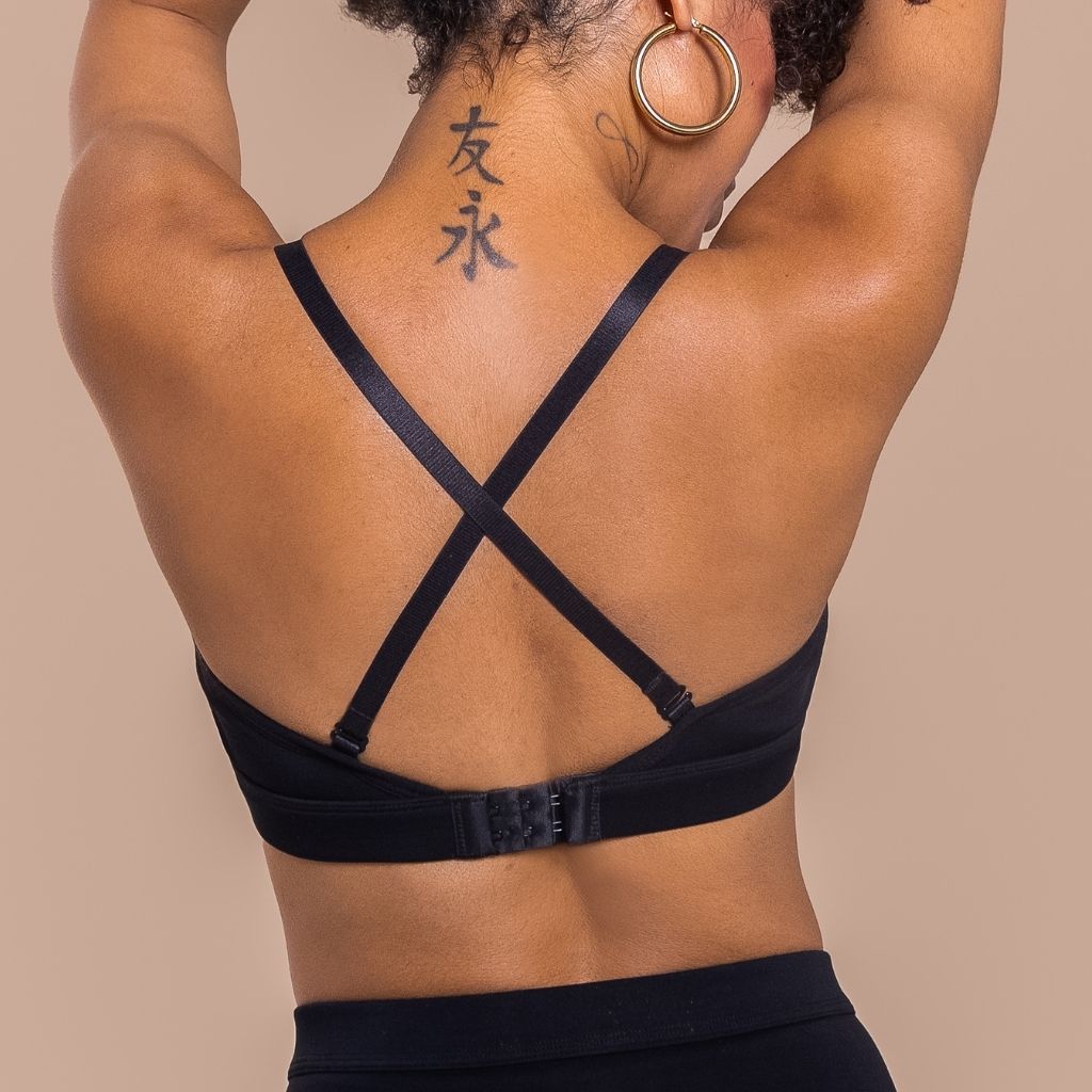 Person wearing a black strappy top against a beige background