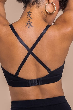 Person wearing a black strappy top against a beige background