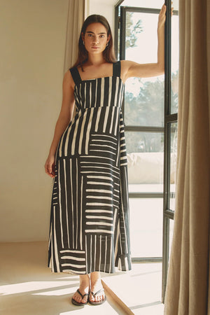 Woman in a black and white striped dress standing in a room with a large window.