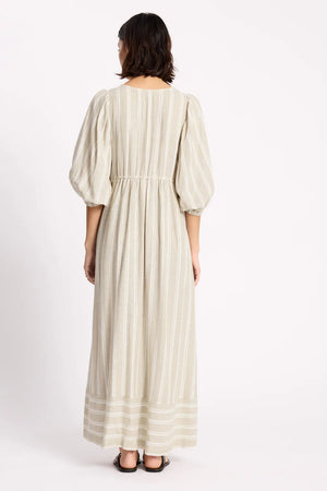 Woman wearing a long, light-colored dress with puffed sleeves on a white background