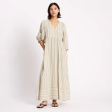 Woman wearing a long, light-colored dress with stripes on a white background