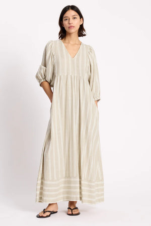 Woman wearing a long, light-colored dress with stripes on a white background