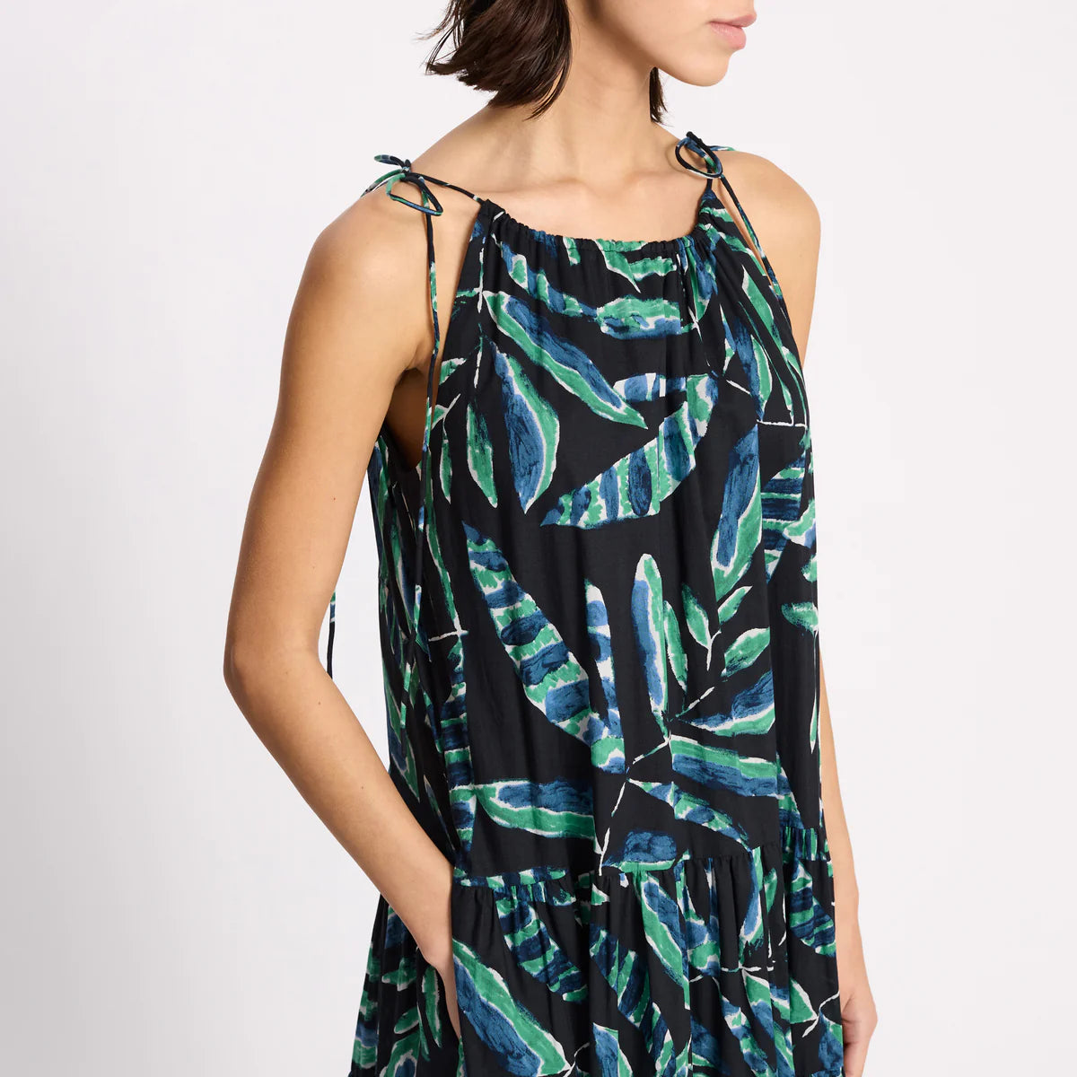 Woman wearing a sleeveless dress with green leaf pattern on a white background