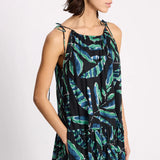 Woman wearing a sleeveless dress with green leaf pattern on a white background