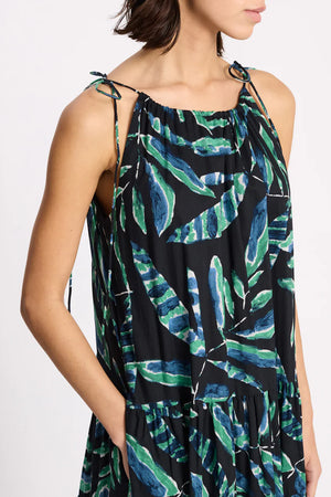 Woman wearing a sleeveless dress with green leaf pattern on a white background